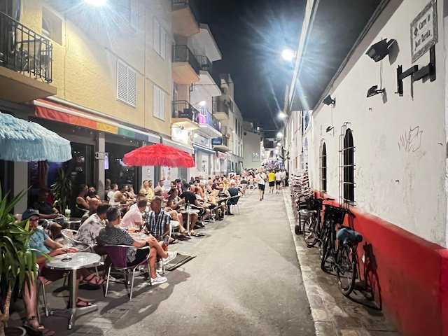 Busy street with outdoor tables, gay bars in Sitges